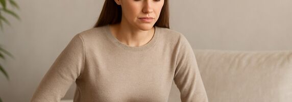 Frau mit Schmerzen im Oberbauch hält ihre Hand auf den Magen - Symbolbild für Gastritis und ganzheitliche Behandlung mit TCM